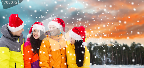 Image of happy friends in santa hats and ski suits outdoors