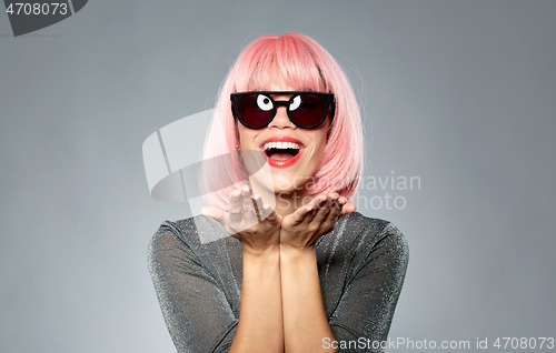 Image of happy woman in pink wig holding something on palms