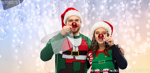 Image of happy couple in christmas sweaters and santa hats