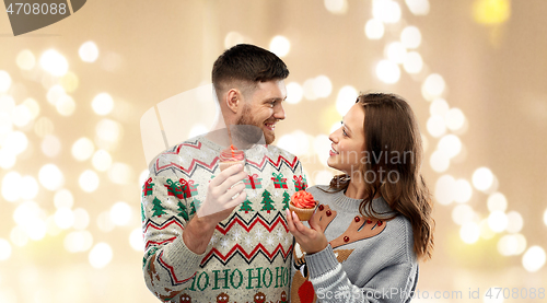 Image of couple with cupcakes in ugly christmas sweaters