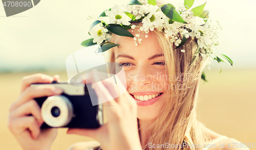 Image of happy woman with film camera in wreath of flowers