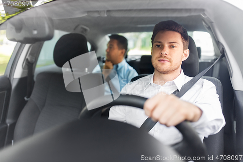 Image of male driver driving car with passenger