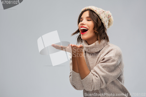 Image of young woman in knitted winter hat sending air kiss