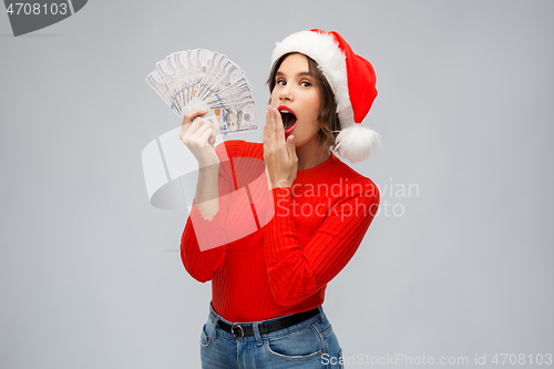 Image of surprised woman in santa hat with money