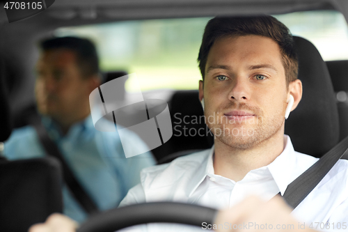 Image of male driver with wireless earphones driving car