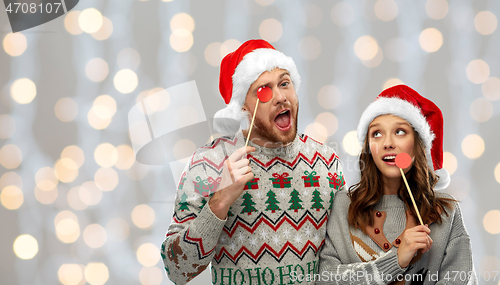 Image of couple with christmas party props in ugly sweaters