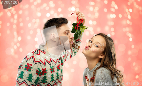 Image of happy couple kissing under mistletoe on christmas