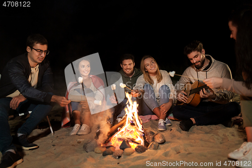 Image of friends roasting marshmallow on camp fire on beach