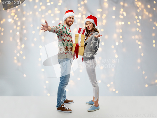 Image of happy couple in christmas sweaters with gifts