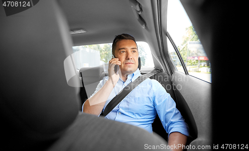 Image of male passenger calling on smartphone in taxi car