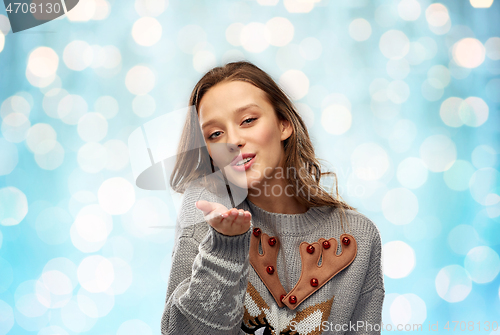 Image of woman in ugly christmas sweater sending air kiss