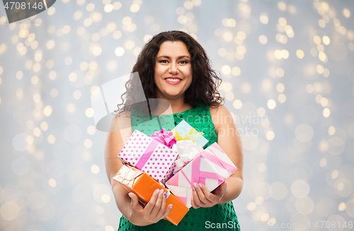 Image of happy woman holding gift boxes over lights