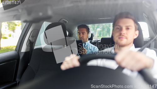 Image of man with tablet pc and headphones riding in car