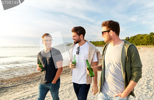 Image of young men with non alcoholic beer walking on beach