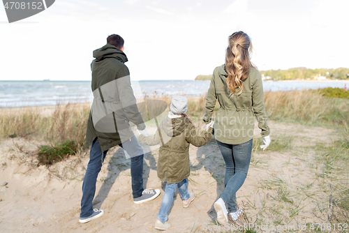 Image of happy family walking along autumn beach