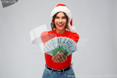 Image of happy woman in santa hat with money on christmas