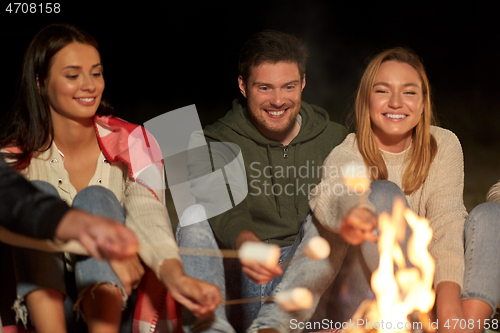 Image of friends roasting marshmallow on camp fire at night