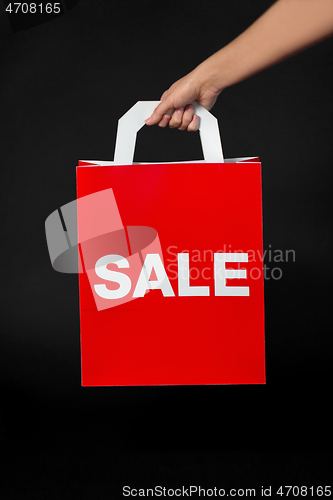 Image of hand holding red shopping bag with sale word