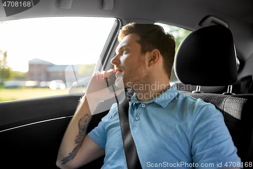 Image of male passenger calling on smartphone in taxi car