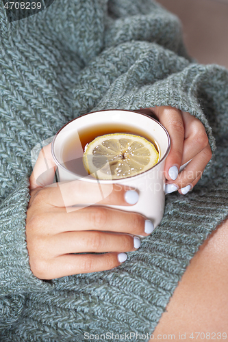 Image of Young woman relaxing tea cup on hands.