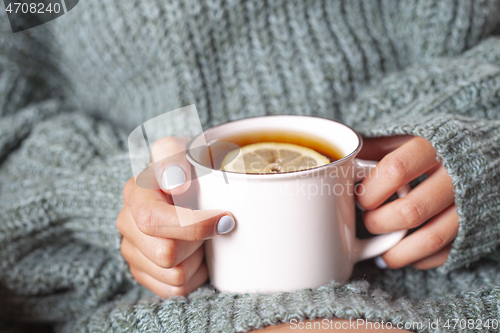 Image of  Young woman relaxing tea cup on hands.