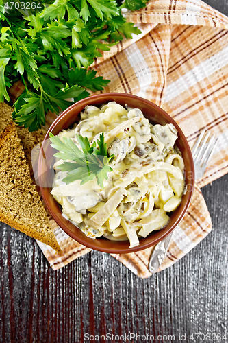 Image of Salad with squid and champignons in bowl on dark board top