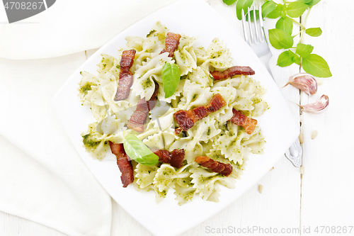 Image of Farfalle with pesto and bacon in plate on board top