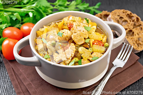 Image of Chicken with vegetables and peas in saucepan on table