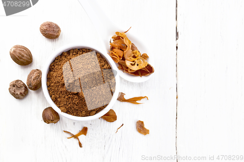 Image of Nutmeg round in bowl and mace in spoon on light board top