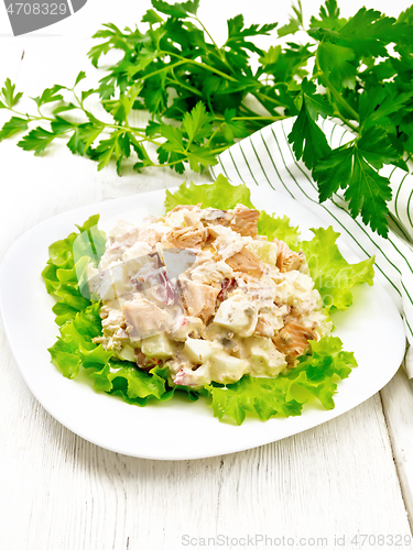 Image of Salad of salmon and cucumber in plate on light wooden board