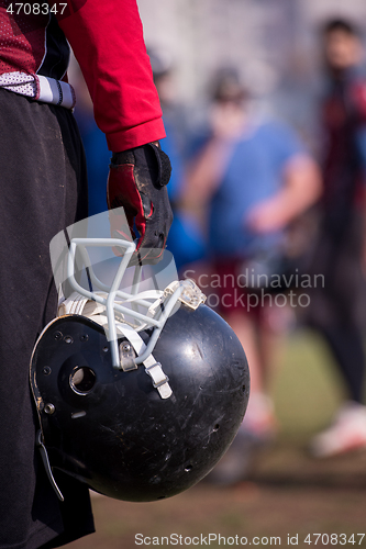 Image of American football player holding helmet