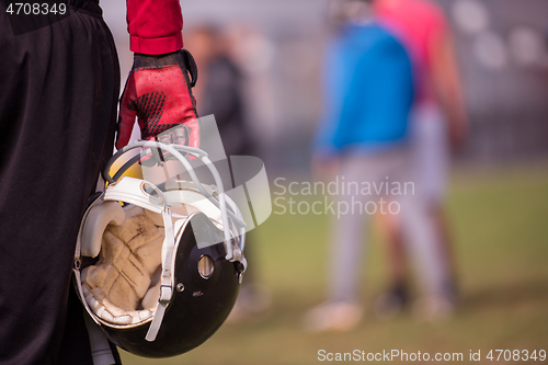 Image of American football player holding helmet