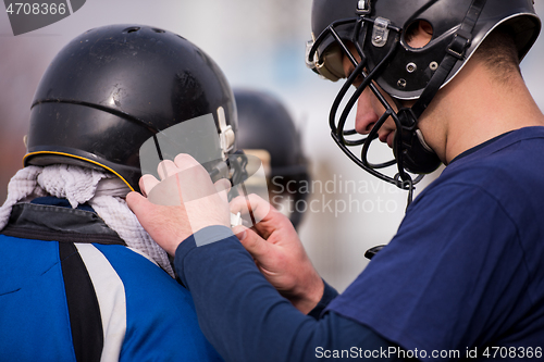 Image of American football players checking helmets
