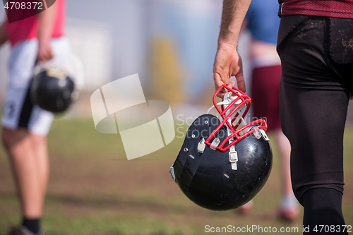 Image of American football player holding helmet