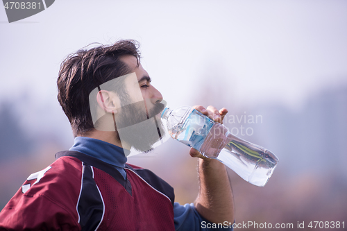 Image of american football player drinking water after hard training