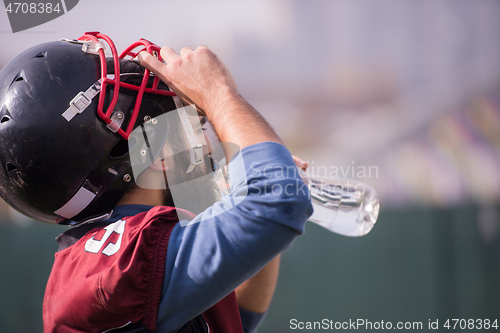 Image of american football player drinking water after hard training