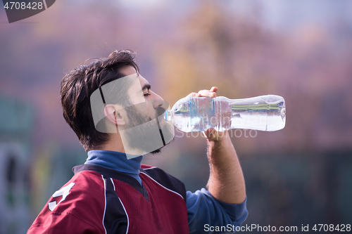 Image of american football player drinking water after hard training