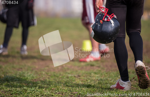 Image of American football player holding helmet