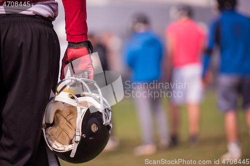 Image of American football player holding helmet