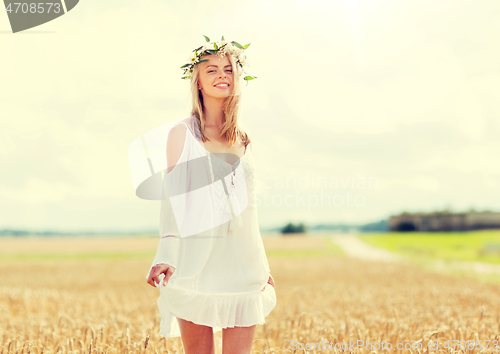 Image of happy young woman in flower wreath on cereal field