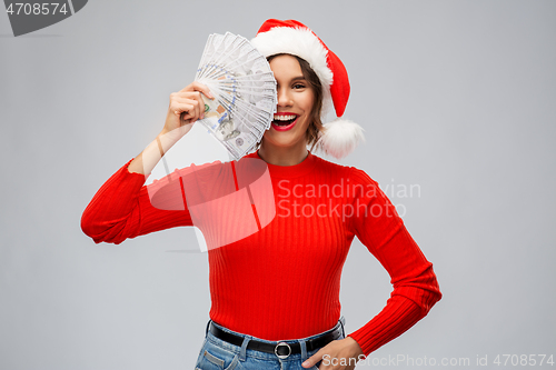 Image of happy woman in santa hat with money on christmas