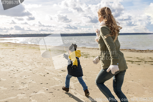 Image of happy family running along autumn beach