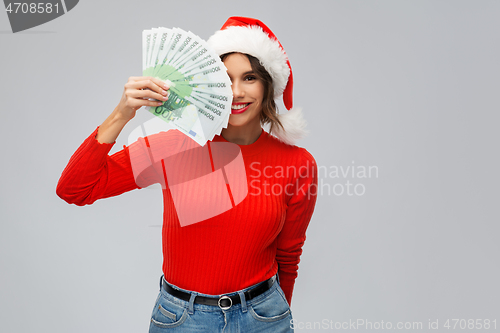 Image of happy woman in santa hat with money on christmas