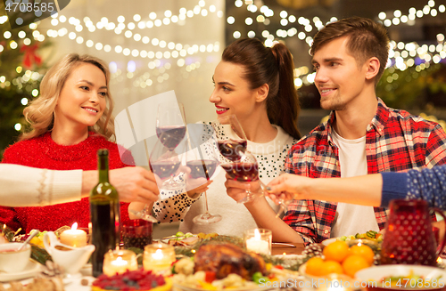 Image of happy friends drinking red wine at christmas party