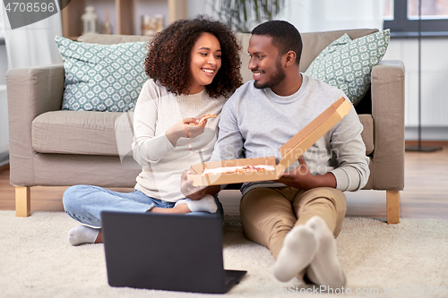 Image of happy african american couple eating pizza at home