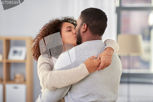 Image of happy african american couple kissing at home