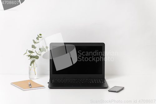 Image of laptop with black screen on white office table