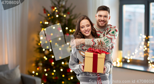 Image of happy couple in christmas sweaters with gift box