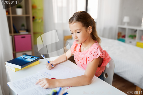 Image of student girl with book writing to notebook at home