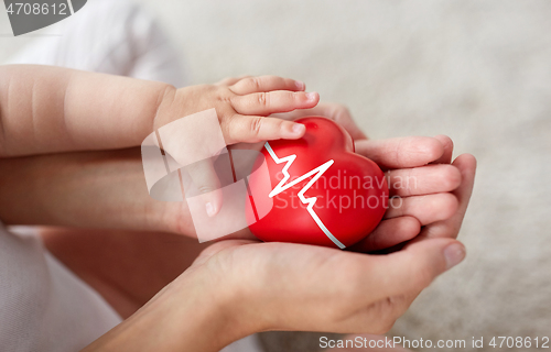 Image of baby and mother holding red heart with ecg line